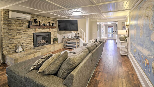 A spacious living room with a stone fireplace, a large sectional sofa, a flat-screen TV, and a world map mural. - Spacious Home w/ Yard, 20 Miles to Olympic NP (Sequim)