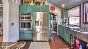 A kitchen with teal cabinets, stainless steel appliances, and a window overlooking a backyard. - Historic Old Colorado City Home w/ Backyard! (Colorado Springs)