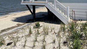 A beachfront house with a balcony and a staircase leading to the entrance.
