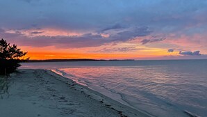 A beach with a calm sea and a sunset sky.