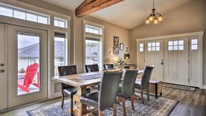 A dining area with a wooden table, black chairs, and a chandelier. There are large windows and a view of the outside. - 'traveler's Retreat' Studio w/ Patio & Yard! (Tualatin)