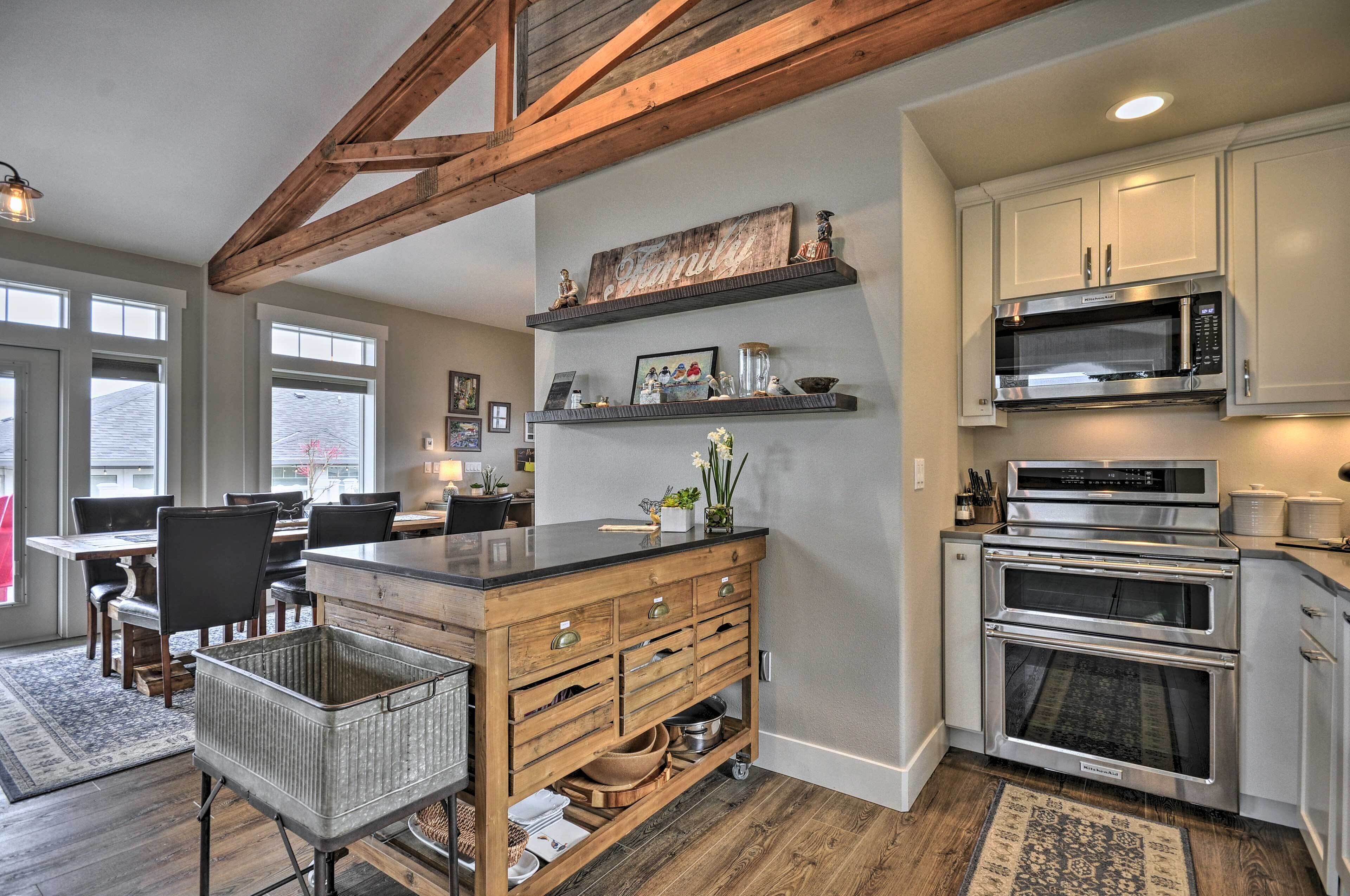 A kitchen with wooden beams, a central island with drawers, a microwave, and an oven.