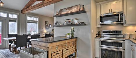A kitchen with wooden beams, a central island with drawers, a microwave, and an oven.