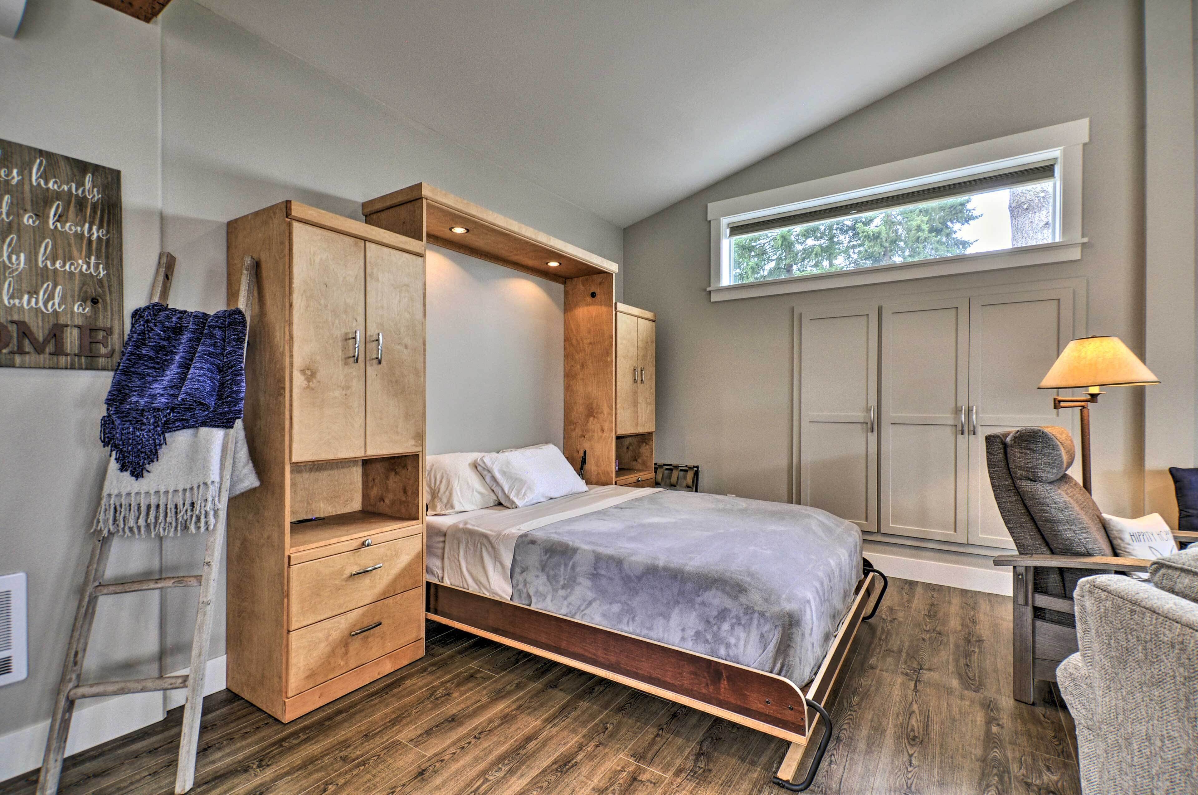 Une chambre à coucher avec un lit, une armoire en bois, une chaise et une fenêtre.