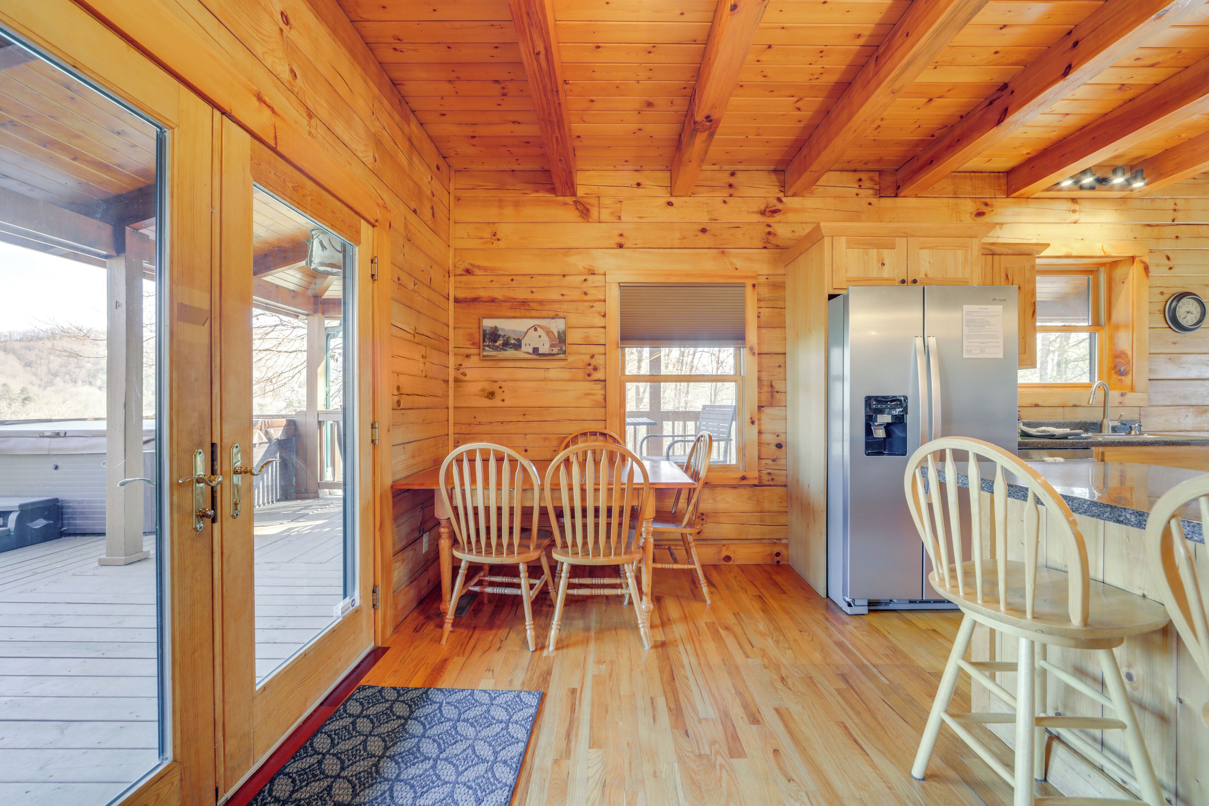 A wooden cabin interior with a dining area, kitchen, and a large window.