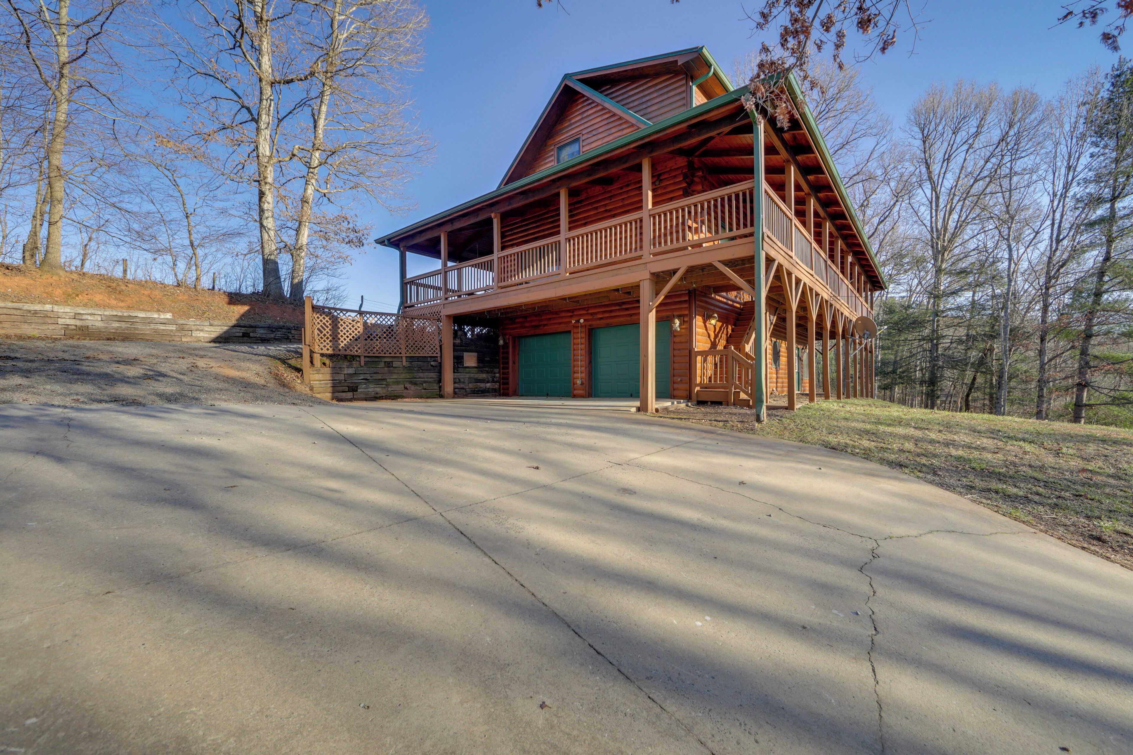 A two-story log cabin with a balcony, a garage, and a driveway.