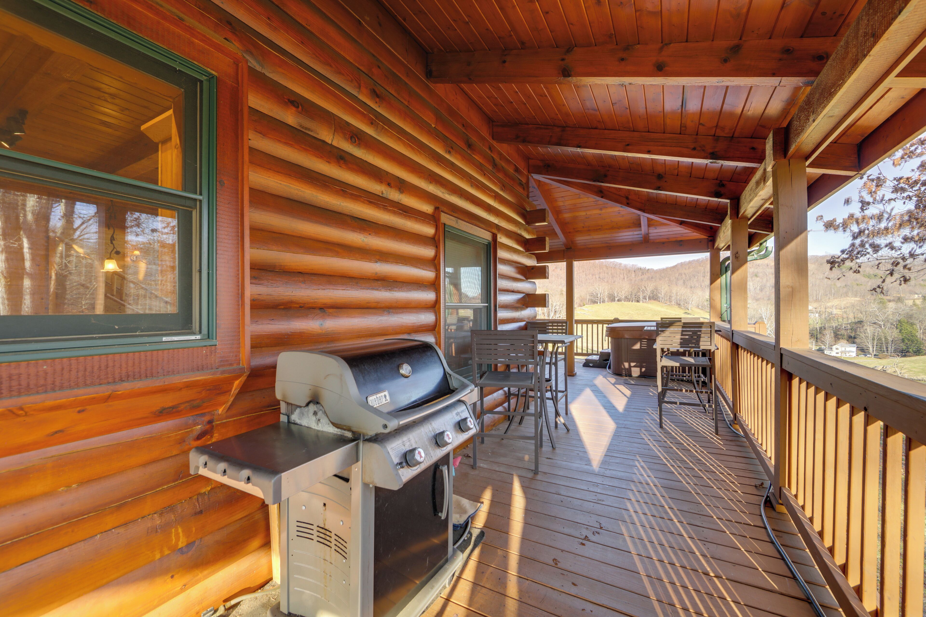 A wooden cabin with a covered porch, a grill, and a table with chairs.
