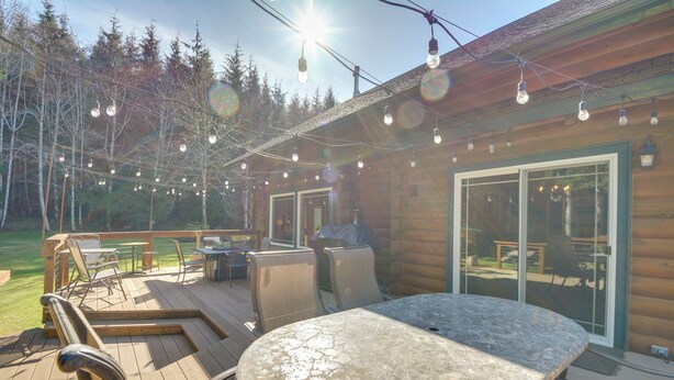 Une terrasse en bois avec des sièges d’extérieur, des guirlandes lumineuses et une grande table.