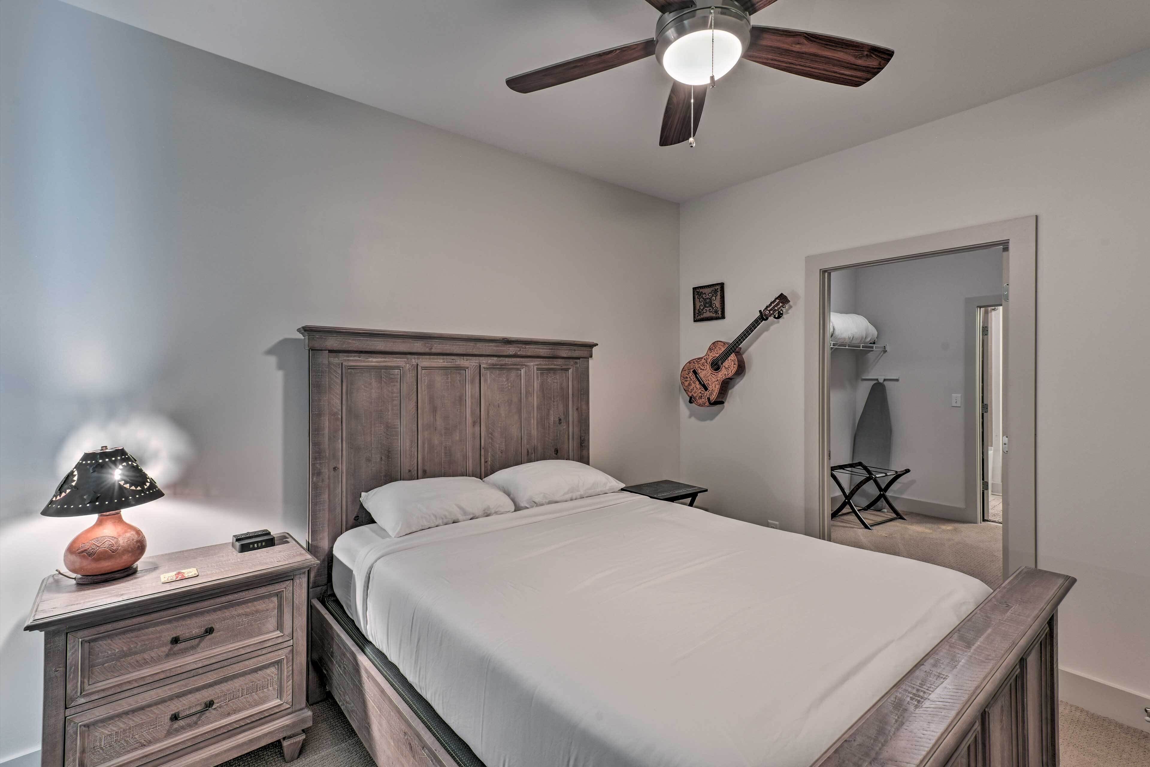 A bedroom with a wooden bed, a nightstand with a lamp, a guitar, and a mirror.