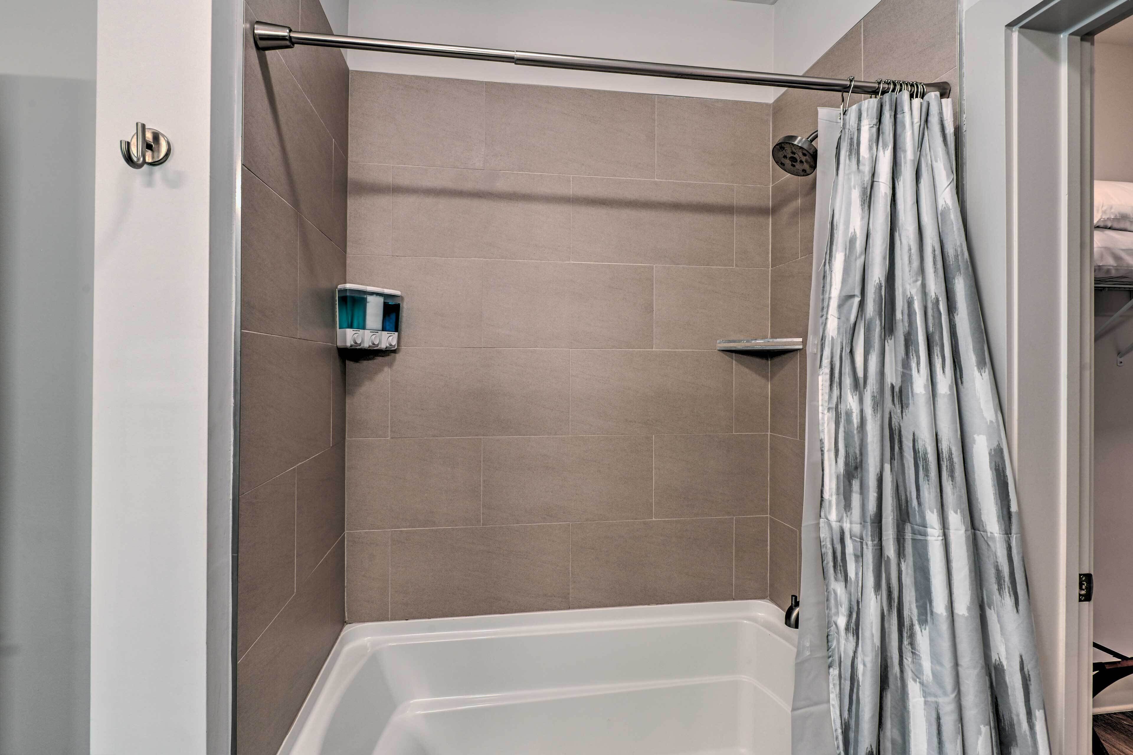A shower area with a bathtub, a showerhead, and a curtain.