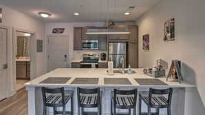 A modern kitchen with a central island, stainless steel appliances, and a bar area with chairs. - Modern Nashville Condo: 7 Mi to Downtown! (Nashville)
