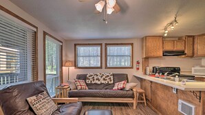 A compact living space with a sofa, ottoman, and a kitchenette area. - Angel Fire Mountainside Condo < 1/2 Mi to Slopes (Angel Fire)