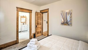 A bedroom with a bed, a mirror, and a door leading to a bathroom. - Cozy Eclectic Home ~ 1 Mi to Downtown Spokane (Spokane)