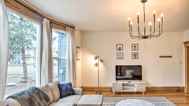 A modern living room with a sofa, ottoman, TV, and chandelier. - Cozy Eclectic Home ~ 1 Mi to Downtown Spokane (Spokane)