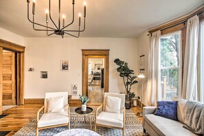 A living room with a chandelier, two armchairs, a sofa, a coffee table, and a large window with curtains. - Cozy Eclectic Home ~ 1 Mi to Downtown Spokane (Spokane)