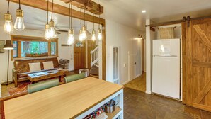 A kitchen with a wooden table, hanging light fixtures, and a white refrigerator. - Tahoe Home in the Pines: Quiet Neighborhood! (South Lake Tahoe)