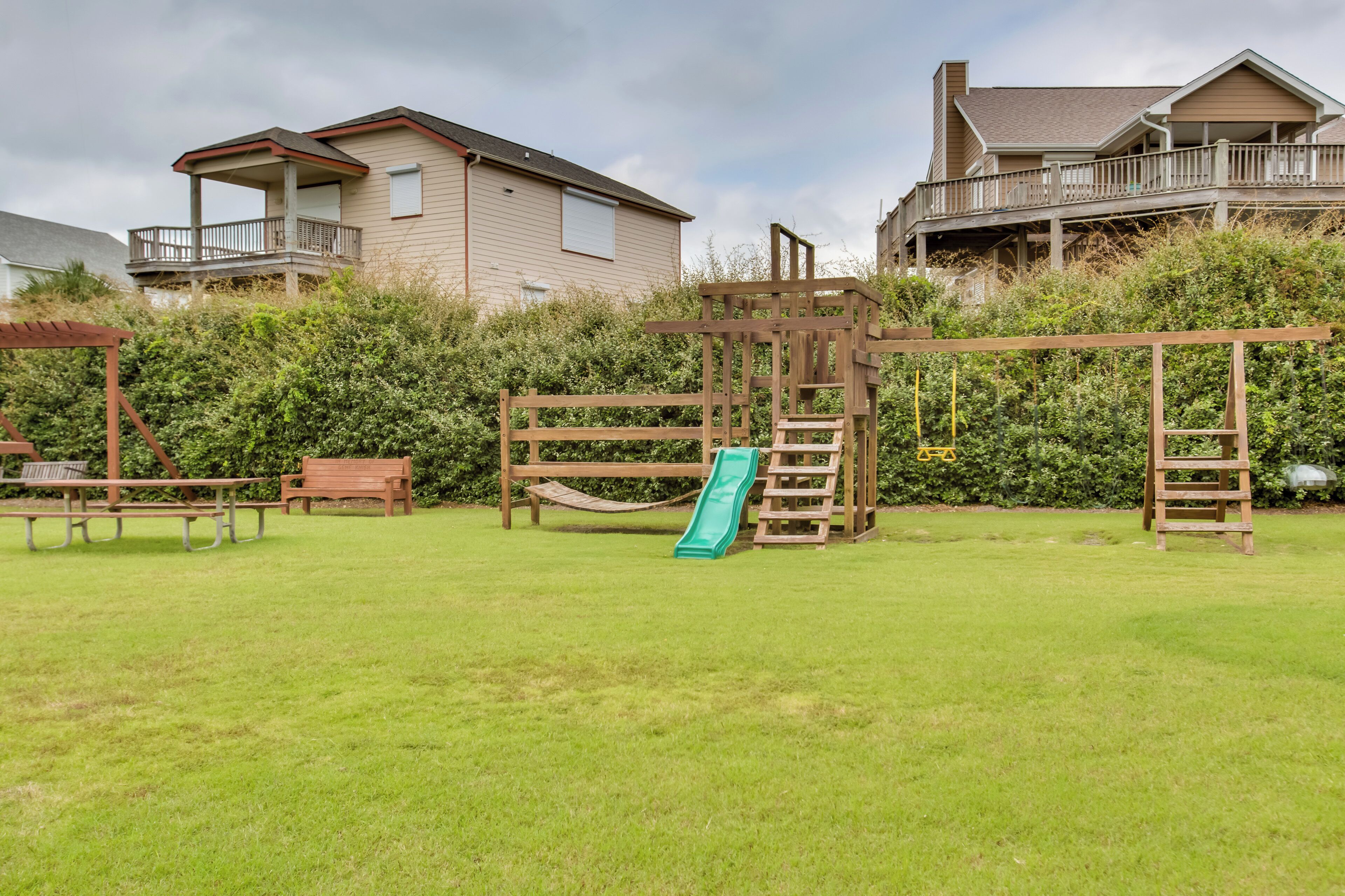 Ein Garten mit einer hölzernen Spielanlage, einer Rutsche und einem Picknicktisch.