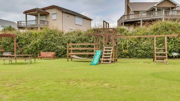 A backyard with a wooden play structure, a slide, and a picnic table.