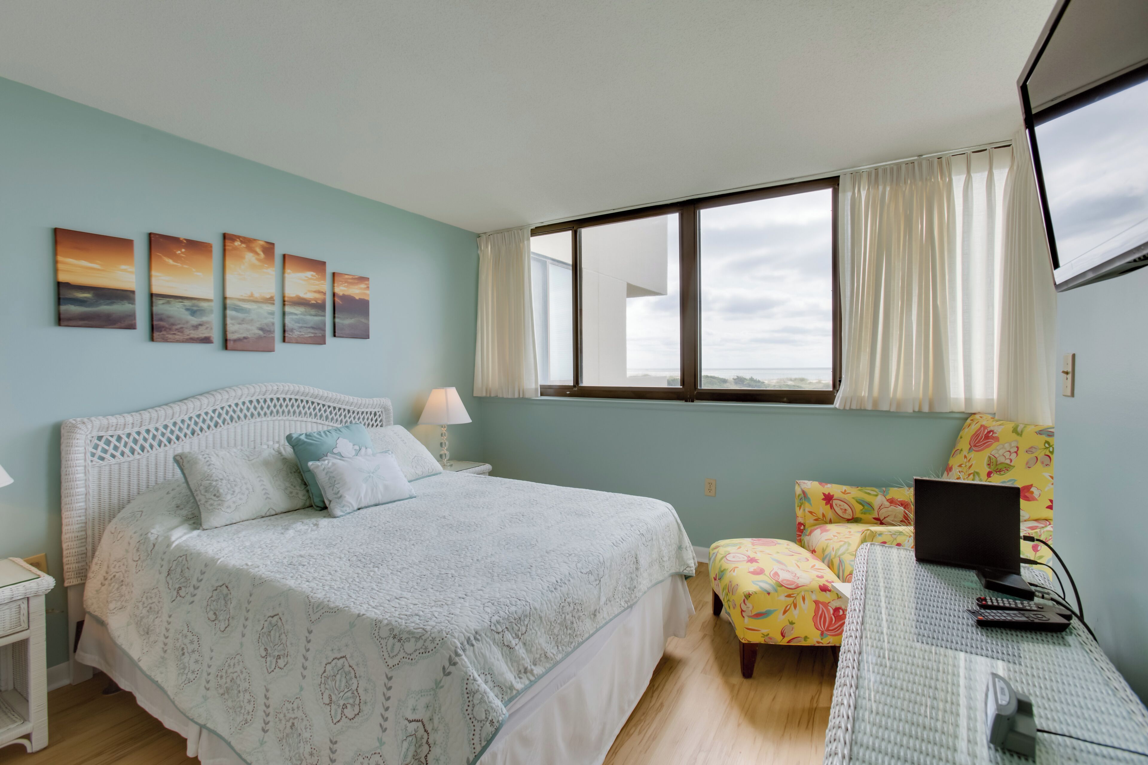 A bedroom with a bed, a desk with a laptop, and a window with curtains.