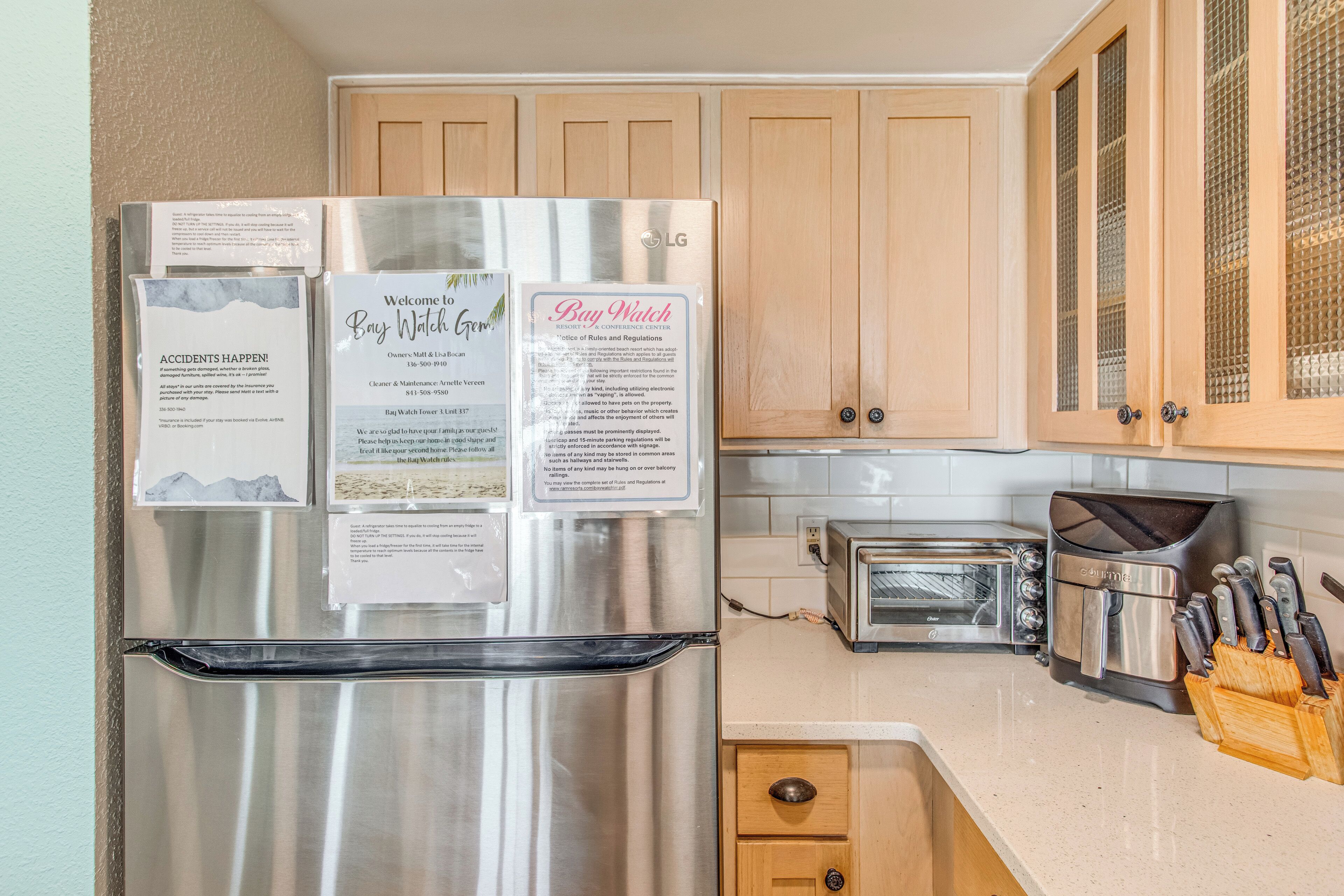 A kitchen with a stainless steel refrigerator, wooden cabinets, a toaster, and a coffee maker.
