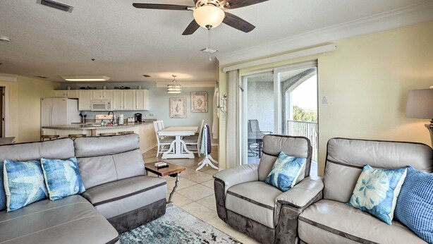 A spacious living area with a ceiling fan, a kitchen in the background, and a sliding glass door leading to a balcony. - St Augustine Condo w/ Pool Access, Walk to Beach! (St. Augustine)