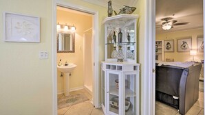 A bathroom with a sink, mirror, and glass cabinet with bottles. - St Augustine Condo w/ Pool Access, Walk to Beach! (St. Augustine)
