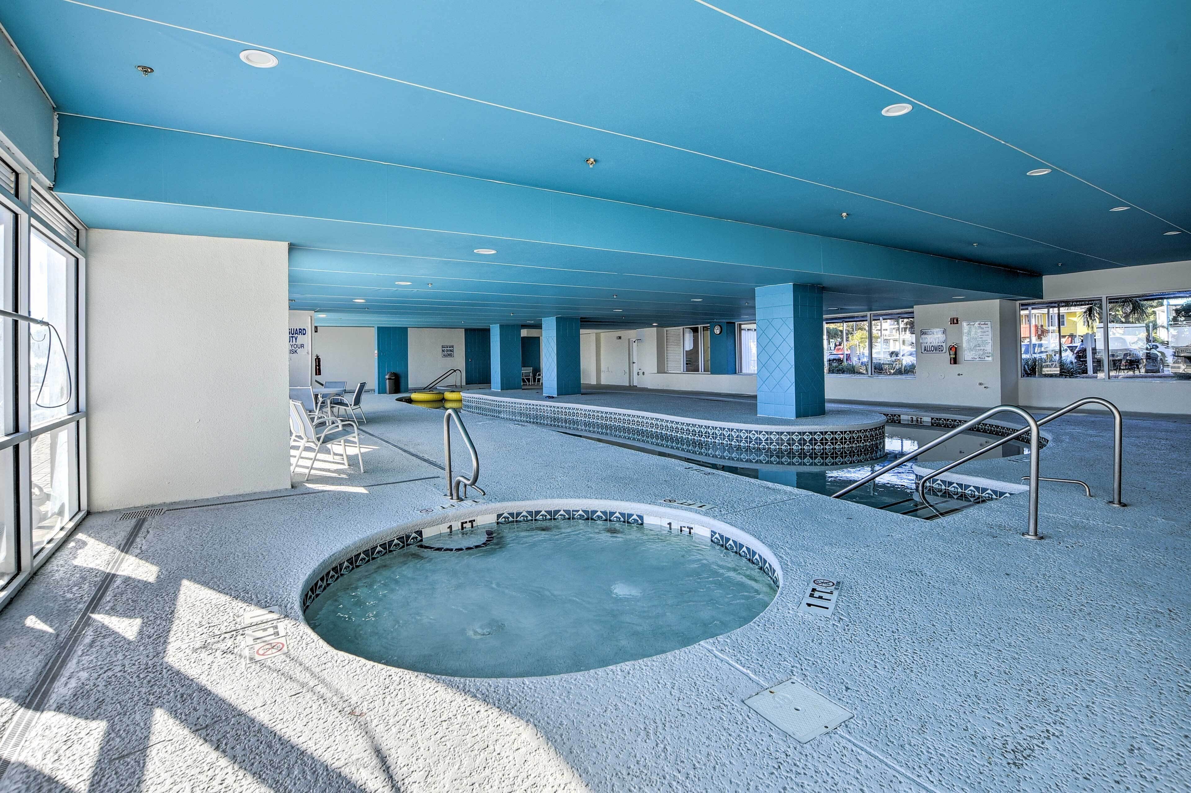 Een zwembadgedeelte met een jacuzzi, glazen wanden en een blauw plafond.