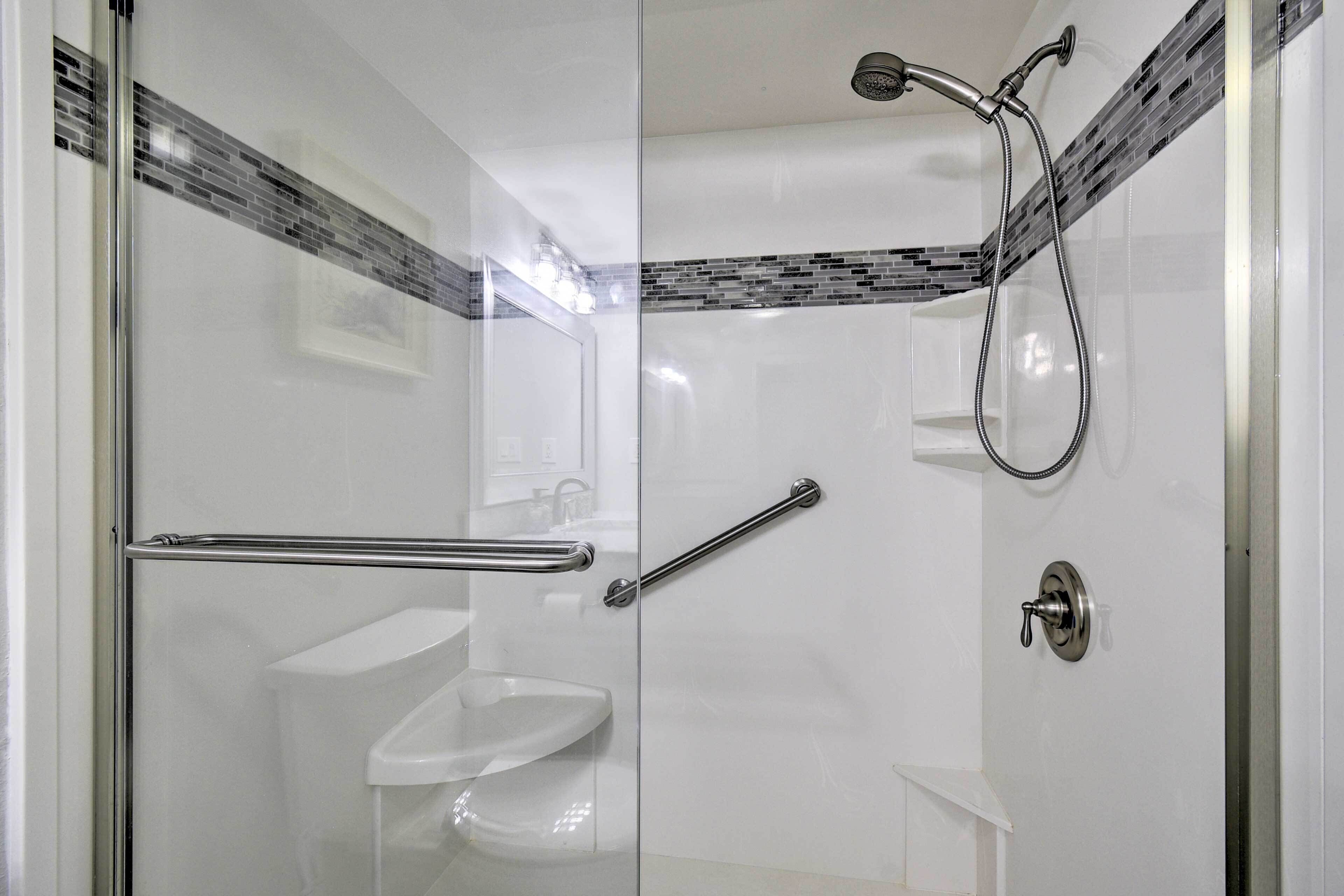 A modern bathroom with a glass shower enclosure, a white sink, and a handheld showerhead.