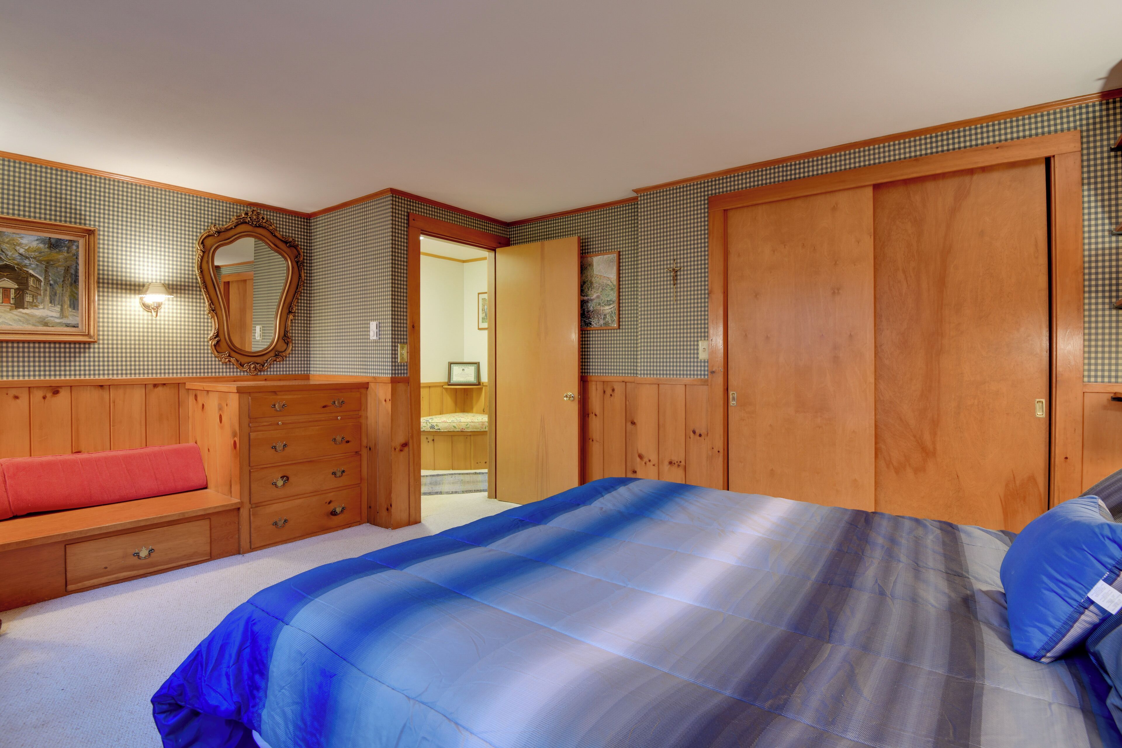 Un dormitorio con una cama grande, un armario de madera y un banco con cajones.