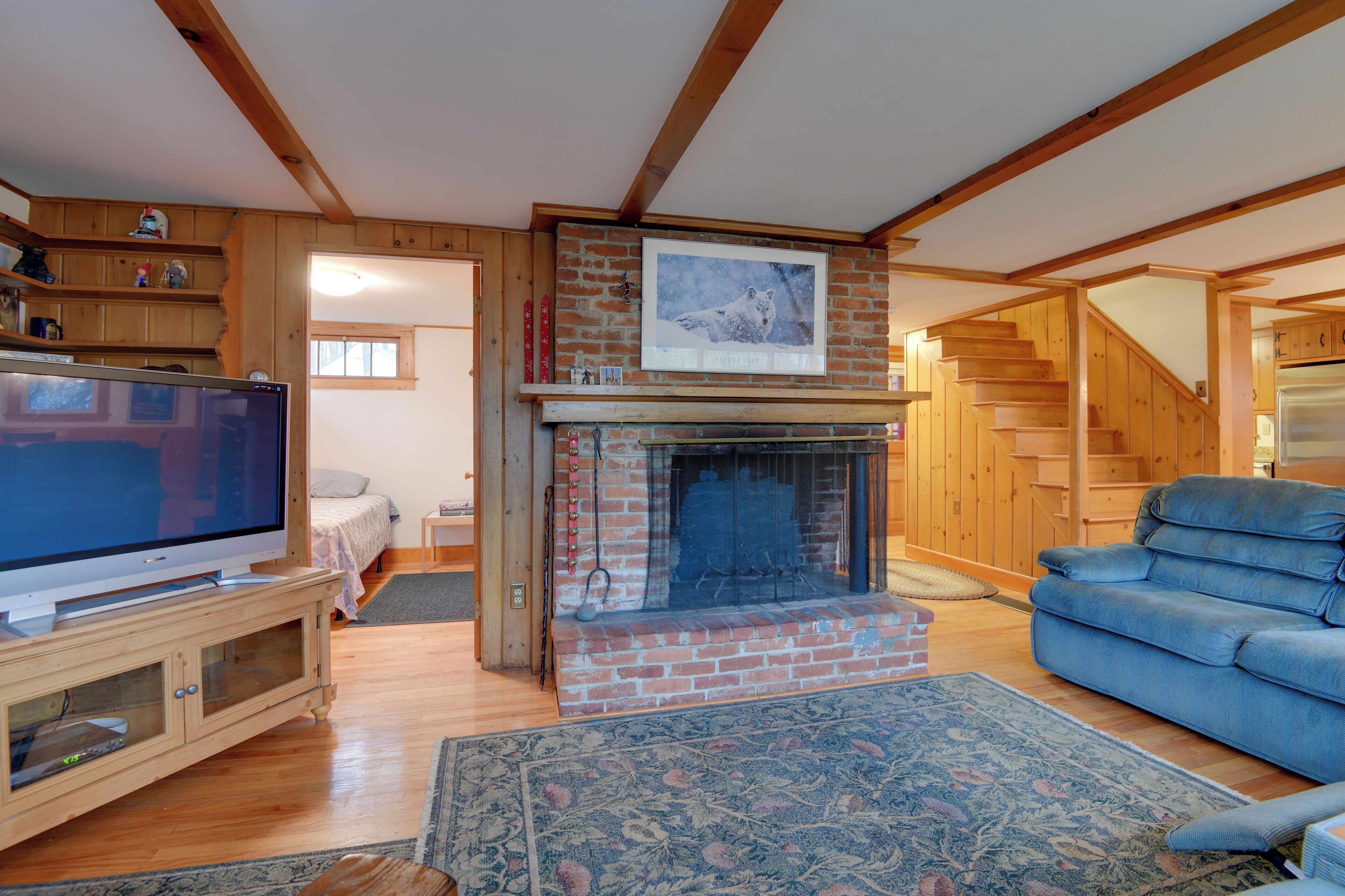 A living room with a fireplace, a television, a sofa, and wooden beams on the ceiling.