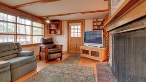 Un salón acogedor con chimenea, televisor, sofá de cuero y estantería.