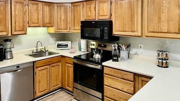 Une cuisine équipée de meubles de rangement en bois, d’un four à micro-ondes, d’un grille-pain, d’une bouilloire et d’une machine à café.