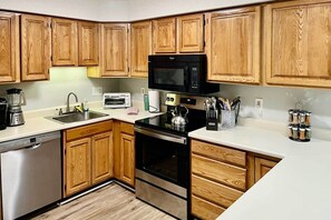 A kitchen with wooden cabinets, a microwave, a toaster, a kettle, and a coffee maker. - Hike, Ski, Explore: Lincoln Condo w/ Pool Access (Lincoln)