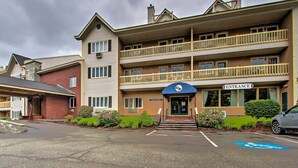 A multi-story hotel with a prominent entrance, a parking lot with a handicapped parking space, and a small garden area. - Hike, Ski, Explore: Lincoln Condo w/ Pool Access (Lincoln)