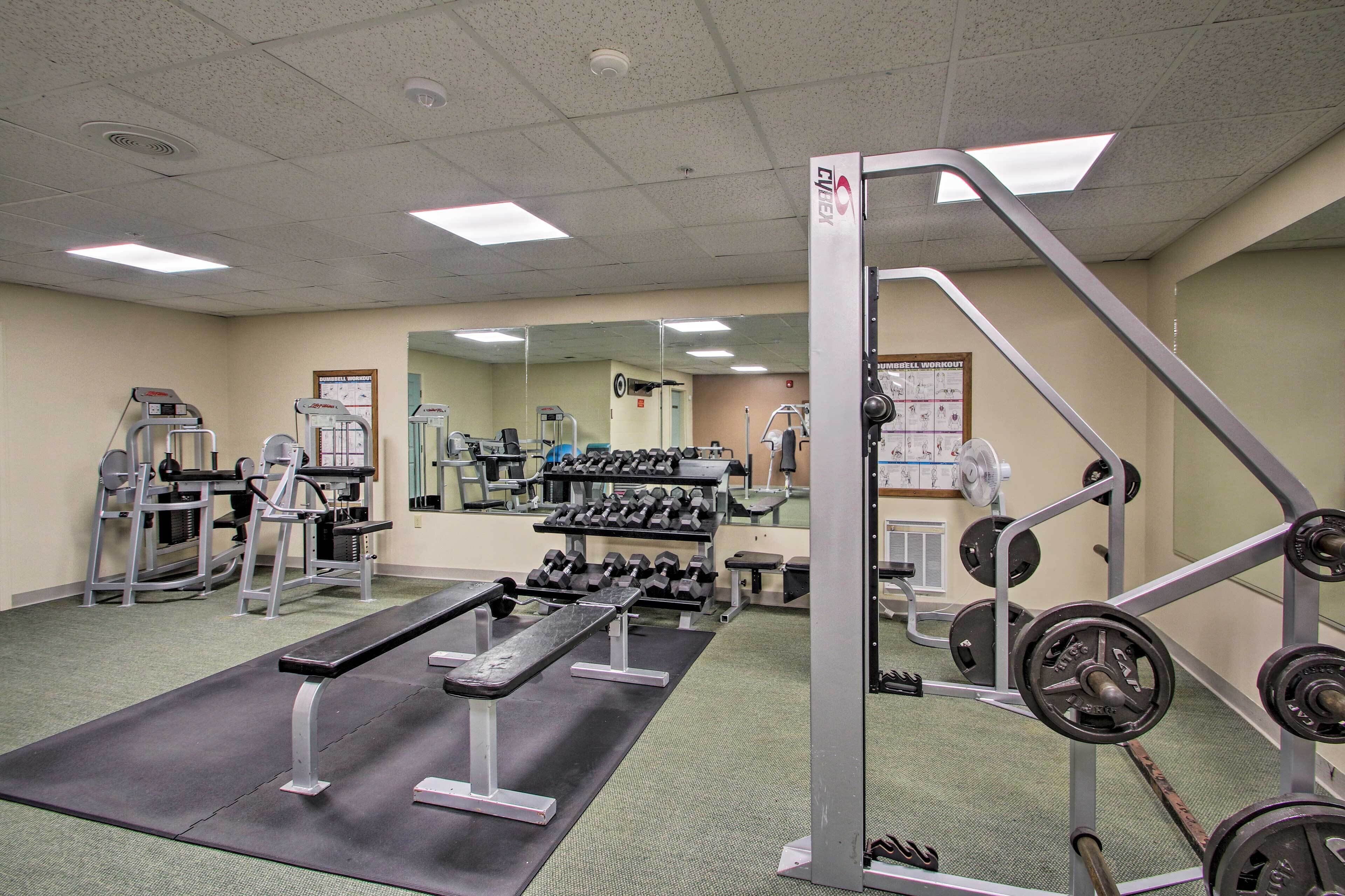 Ett gym med olika typer av träningsutrustning, inklusive hantlar, bänkar och styrketräningsmaskiner.