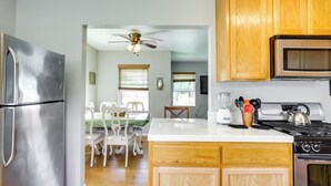A kitchen with wooden cabinets, a stainless steel refrigerator, a stove, and a dining area with a table and chairs.