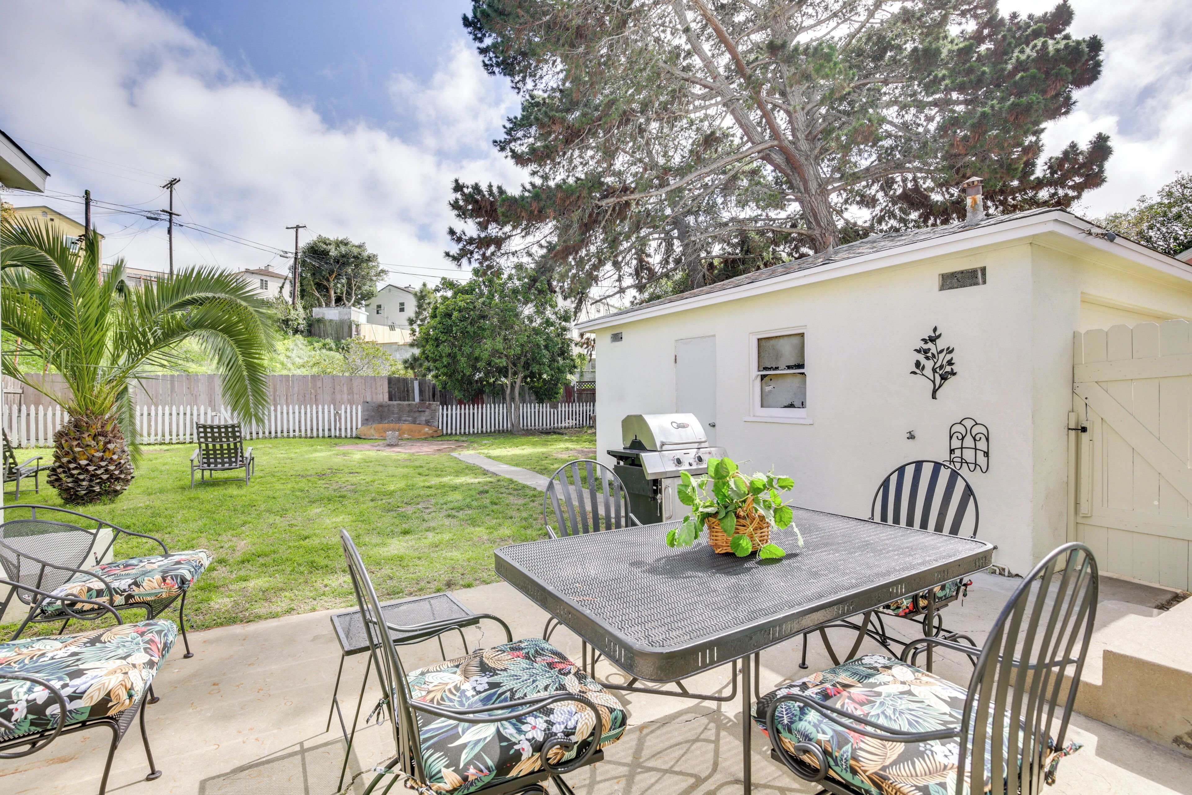 Une terrasse avec une table et des chaises, un barbecue et un petit abri de jardin.