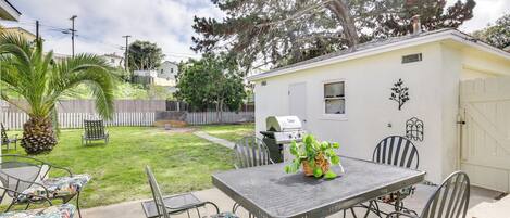 Une terrasse avec une table et des chaises, un barbecue et un petit abri de jardin.