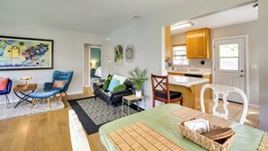 A modern living room with a sofa, chairs, and a dining area with a kitchen in the background.