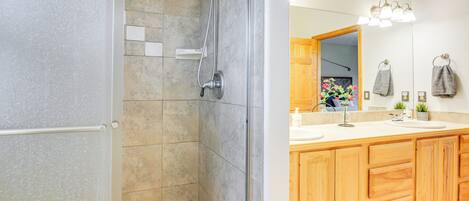 Ein modernes Badezimmer mit Dusche, Waschbecken und Holzschränken.