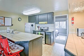 A kitchen with a central island, a stove, and a refrigerator. There is a clock on the wall and a fire extinguisher mounted on the wall. - Quiet South Lake Tahoe Condo ~ 1 Mi to Keys Beach! (South Lake Tahoe)