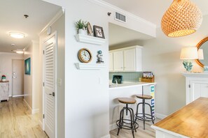 A kitchen with white cabinets, a wooden countertop, two stools, and a hanging light fixture. - Okaloosa Island Escape: Bayfront Condo Near Beach (Fort Walton Beach)