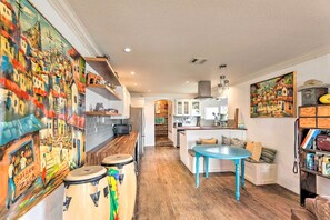 Een ruime keuken met houten vloeren, een centraal eiland en een eethoek met een blauwe tafel.