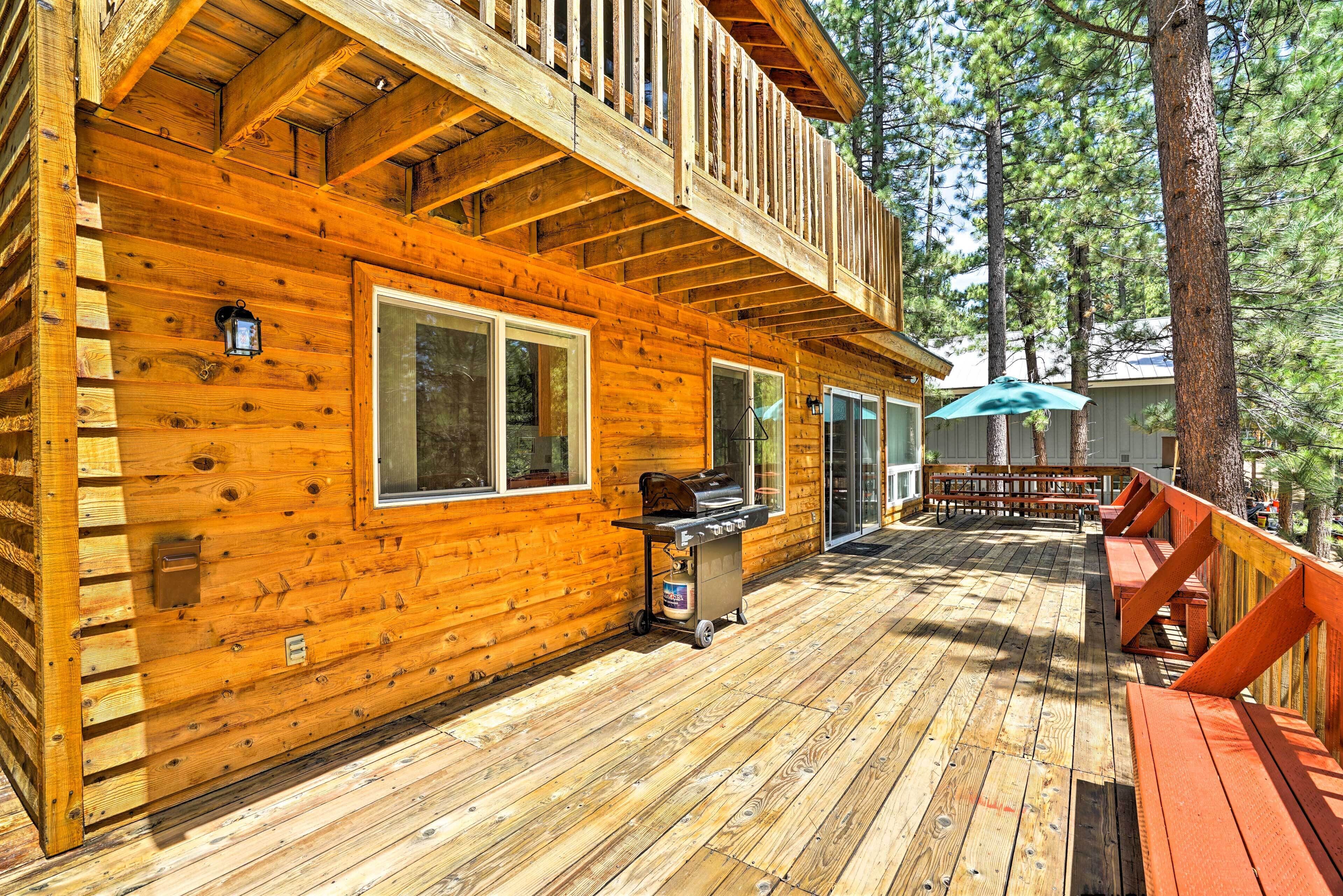 A wooden cabin with a deck, a barbecue grill, and outdoor seating.