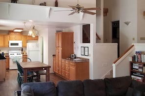 A spacious living area with a dining table, a sofa, and a kitchen with wooden cabinets and appliances.