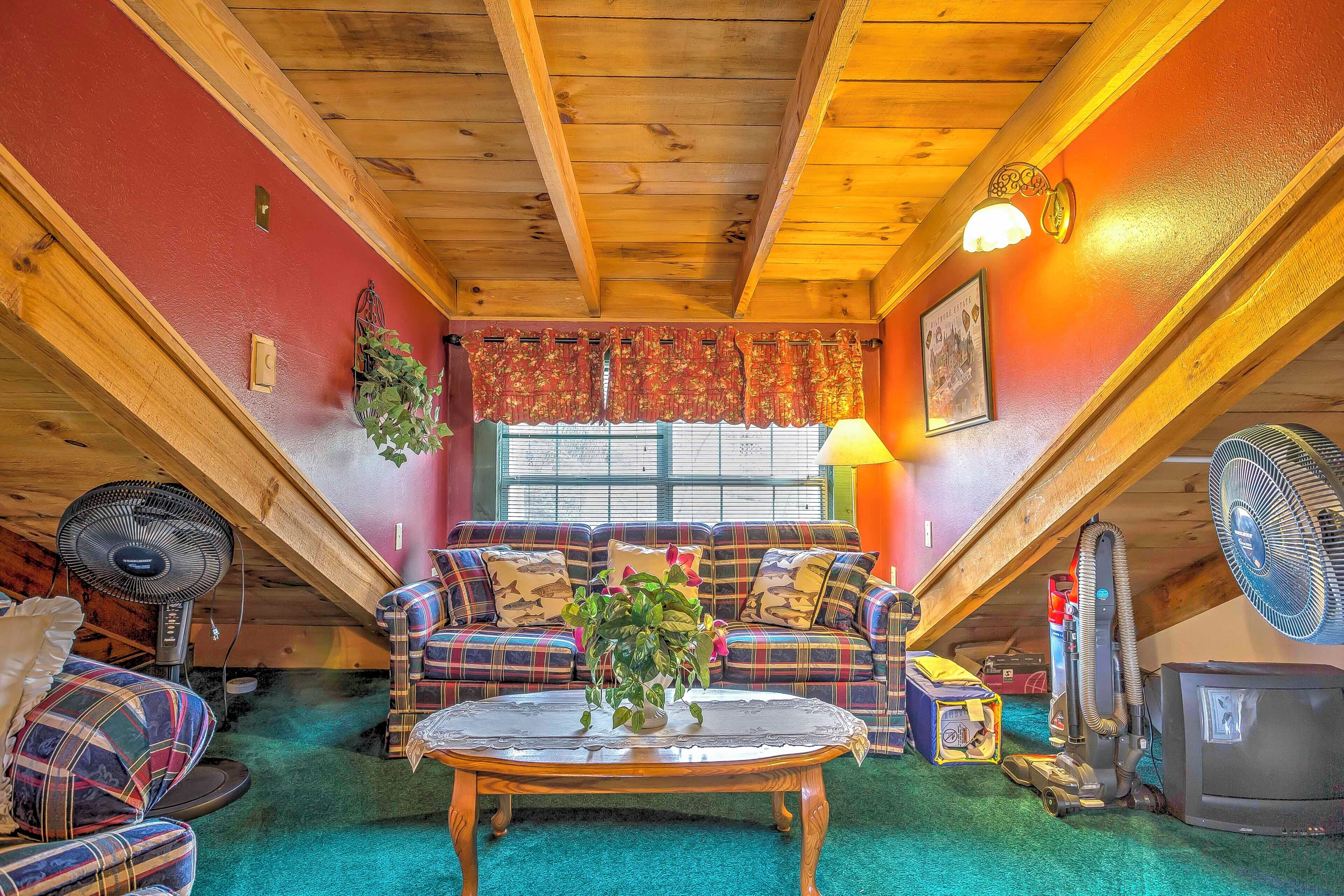 Une pièce mansardée chaleureuse, avec un canapé à carreaux, un plafond en bois et une moquette verte.