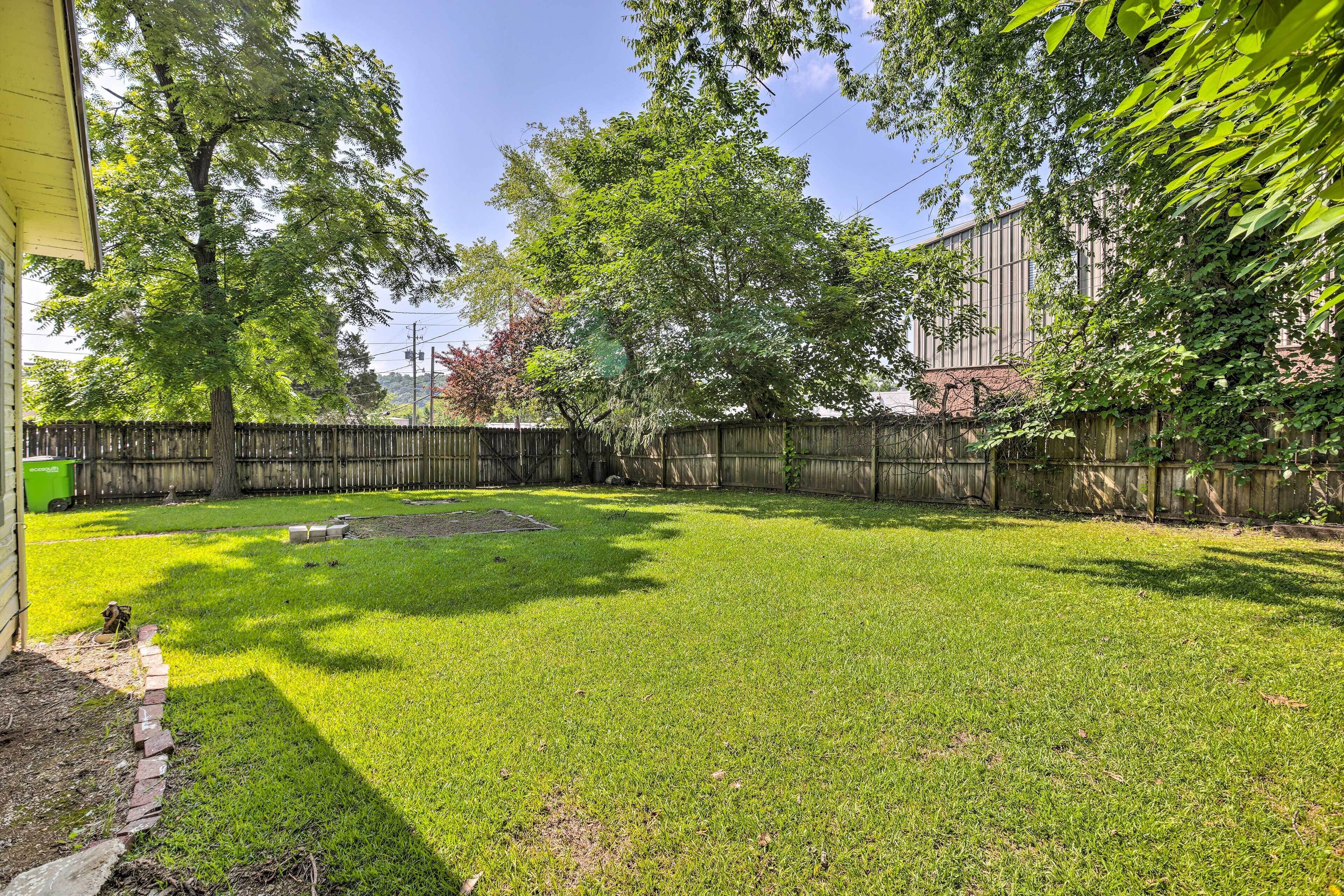 A backyard with a well-maintained lawn, a wooden fence, and a large tree providing shade.