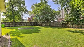 A backyard with a well-maintained lawn, a wooden fence, and a large tree providing shade.