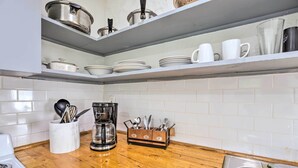 A kitchen with white tiled backsplash, wooden countertop, stainless steel sink, and shelves with dishes and cookware. - Quaint Leeds Studio w/ Yard ~ 18 Mi to Birmingham! (Leeds)