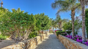 A stone pathway flanked by lush greenery and flowering plants. - Cabo Pedregal Condo: Ocean View & 2 Infinity Pools (Cabo San Lucas)